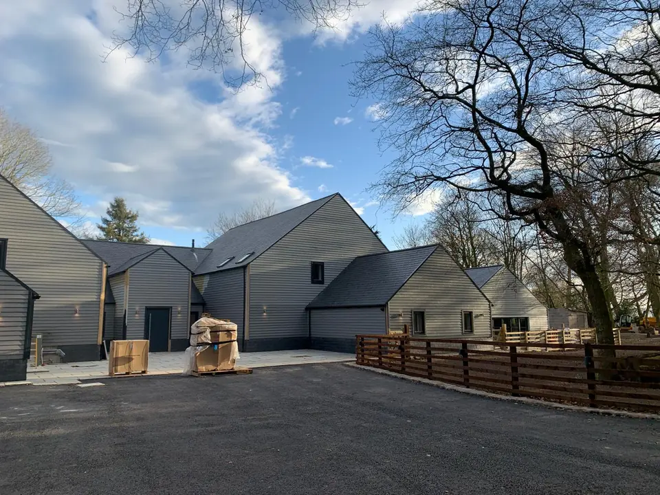 Group of barn buildings finished in grey cladding around a tarmac courtyard