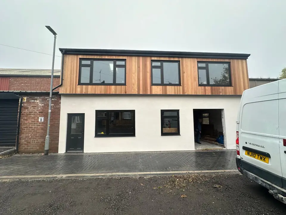Two-storey commercial building with white render and timber cladding