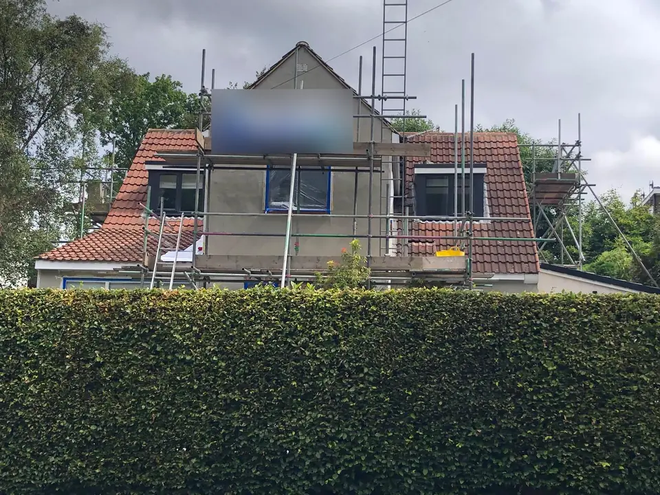 Detached house before re-rendering, with tired brown exterior walls and scaffolding up