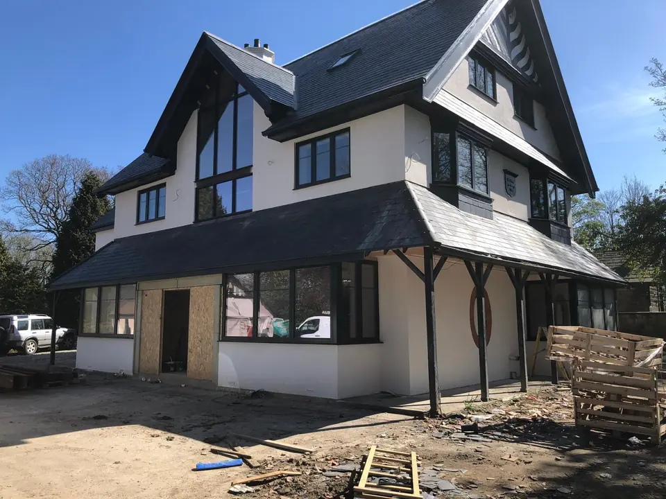 Side view of a large new-build home with fresh white render