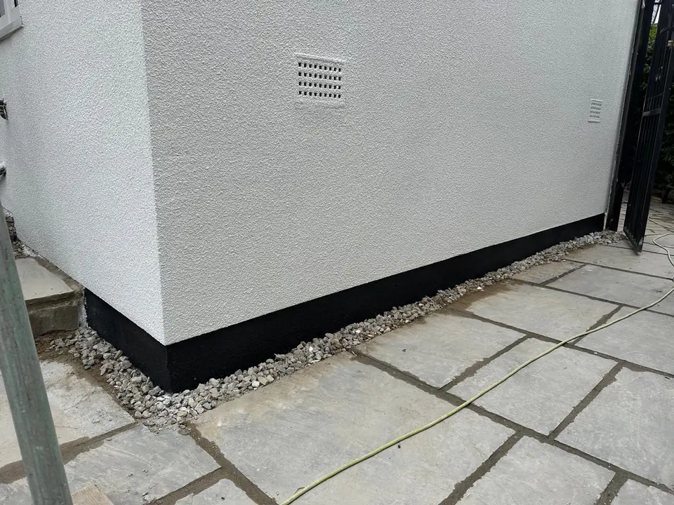Close-up of a crisp render line above a dark plinth and paving