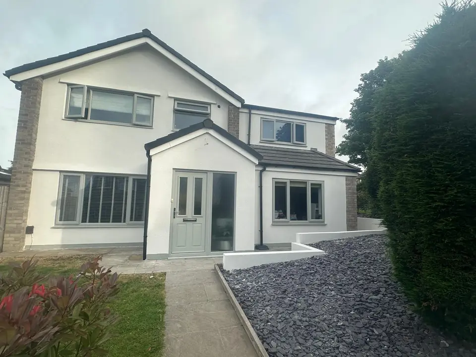 Semi-detached house with a fresh white render finish, grey windows and a slate-chip front garden