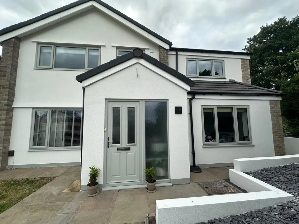 The same semi-detached house finished in smooth white render, with grey windows, a grey front door and new rendered garden walls