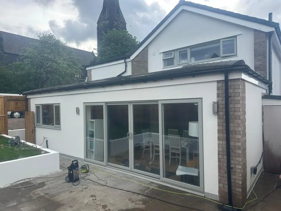 Rear extension in white render with large sliding doors, brick corner piers and a paved patio