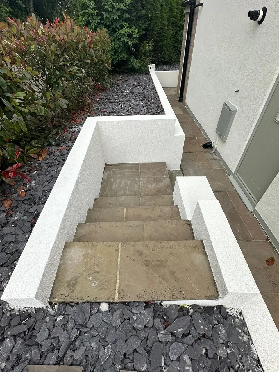 Garden steps between low white rendered walls, with slate chippings on either side