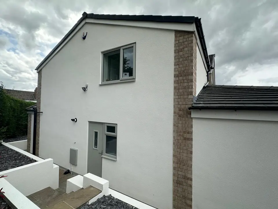 Side elevation in white render with a grey door, a brick corner and rendered walls lining the steps